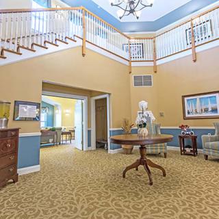 A brightly lit lobby with a central table and staircase.