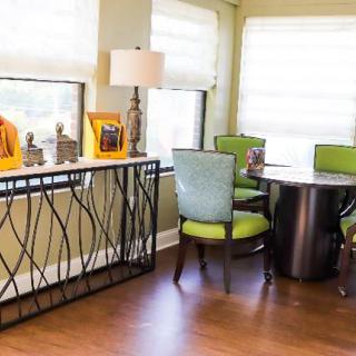A cozy living room corner with a round table and vibrant green chairs, accented by decorative pieces on a console table.