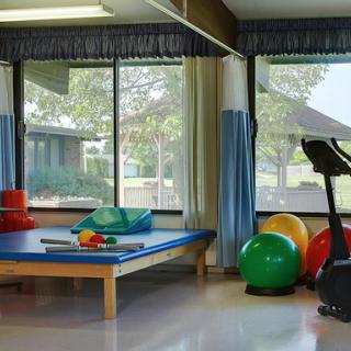 A bright and inviting therapy room featuring exercise equipment and colorful fitness balls.