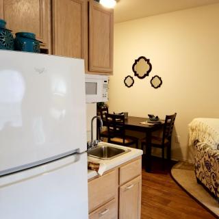 A cozy apartment featuring a compact kitchen area with a small dining table and bed.
