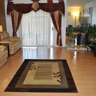 A cozy living room with a central rug, elegant curtains, and comfortable seating.