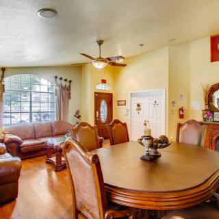 A cozy living and dining area with a wooden table, chairs, sofas, and a ceiling fan.