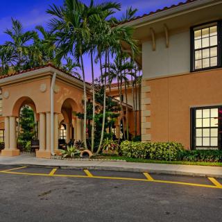 Tropical style building entrance illuminated at night, surrounded by palm trees.