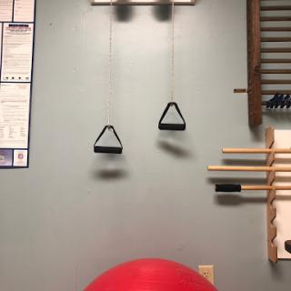 A wall-mounted exercise setup featuring pulleys and a stability ball.