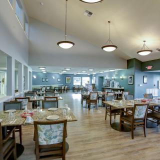 A spacious dining area with modern decor, featuring multiple tables and chairs, elegant lighting, and a welcoming atmosphere.