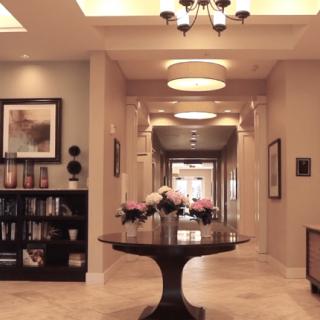 A beautifully decorated lobby with a central table, flowers, and a bookshelf in the background.