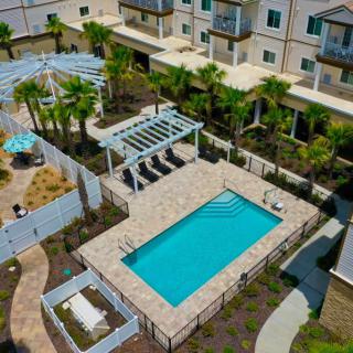 Aerial view of a residential complex featuring a swimming pool, pergola, and landscaped gardens with palm trees.