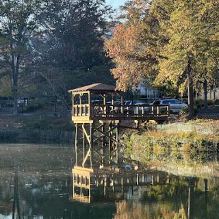 A serene lakeside view featuring a wooden dock surrounded by autumn foliage.