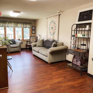 A cozy living room with sofas, armchairs, and a decorative shelf against hardwood flooring.