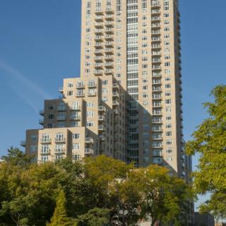 A tall skyscraper surrounded by trees on a clear day.