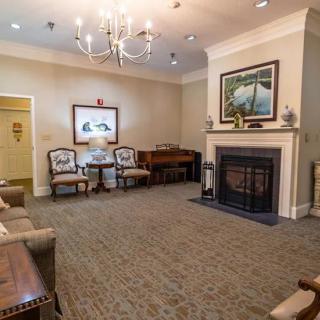 A cozy living room with a fireplace, chandelier, and seating area.