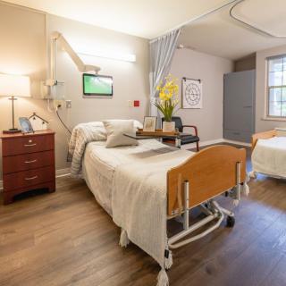 A clean and well-organized hospital room with a patient bed and modern furnishings.