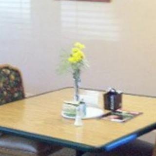A restaurant table with a vase of yellow flowers.