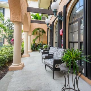 A charming outdoor patio area with elegant arches, columns, and comfortable seating surrounded by lush greenery.