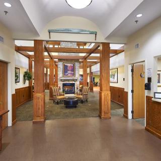 A spacious lobby with wooden beams, comfortable seating, and a central fireplace.