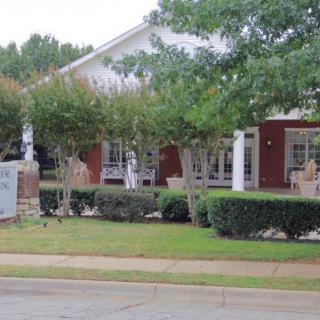 A large red-brick building with white columns and a neatly landscaped front yard.