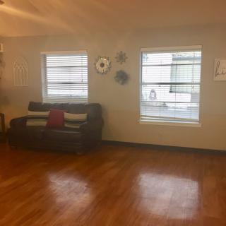 A cozy living room with a couch, wooden floors, and natural light from windows.