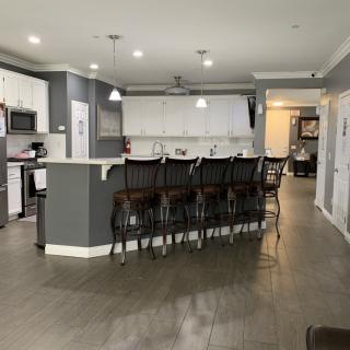 A modern kitchen with a stylish island and bar stools, featuring white cabinets and pendant lighting.