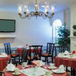 A cozy dining room with elegant table settings and a chandelier.