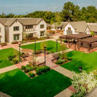 Aerial view of a well-maintained courtyard with buildings, lush gardens, and walking paths.