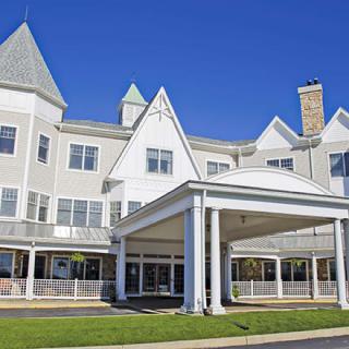 A sunny view of a large building with an entrance porch and multiple windows.
