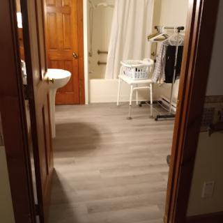 A view of a bathroom from the doorway, featuring a laundry basket and shower area.