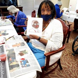 A resident proudly displays her artwork during a creative session in a community center.