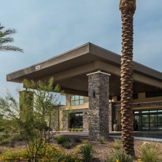 A modern building exterior with palm trees and landscaped surroundings.