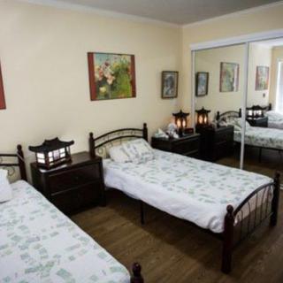 A cozy bedroom with twin beds, decorated with lamps and paintings.