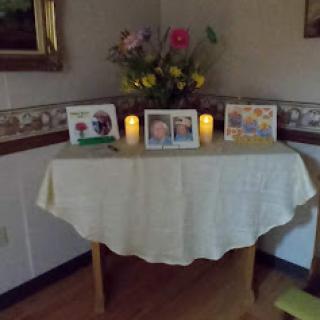 A serene home altar adorned with flowers, candles, and cherished photographs.
