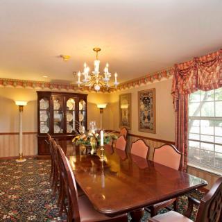 An elegant dining room featuring a long wooden table, a chandelier, and a china cabinet.