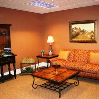A cozy living room with an orange color scheme, featuring a patterned sofa, wooden coffee table, and tasteful decor.