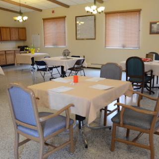 A spacious dining area with neatly arranged tables and chairs, ready for a community gathering.