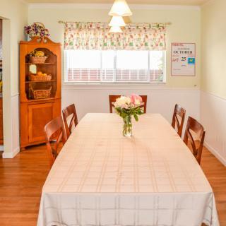 A cozy dining room with a table set for a meal, adorned with fresh flowers.