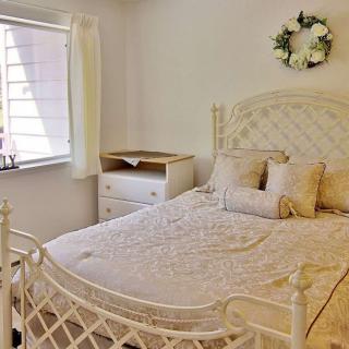 A cozy bedroom with white decor and natural light.