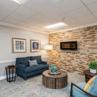 A cozy living room with a blue sofa, coffee table, and decorative brick wall.