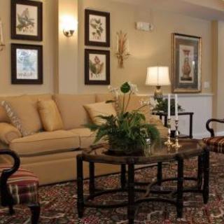 A cozy living room with a beige sofa, coffee table, artwork on the walls, and warm lighting.