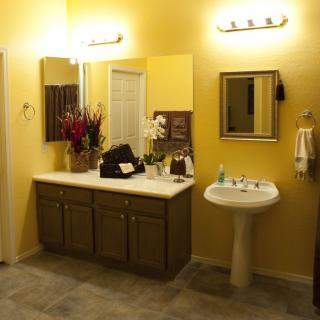 A well-lit bathroom with yellow walls featuring a vanity, sink, and mirrors.