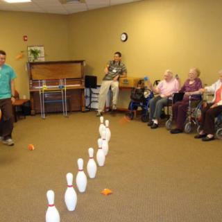 A group of seniors participates in an indoor bowling activity.