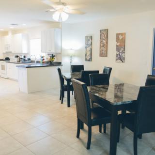 A modern dining area adjacent to a kitchen with sleek furnishings and elegant decor.
