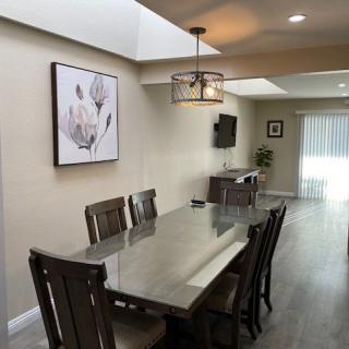 A modern dining room featuring a long table with chairs, contemporary lighting, and artwork on the wall.