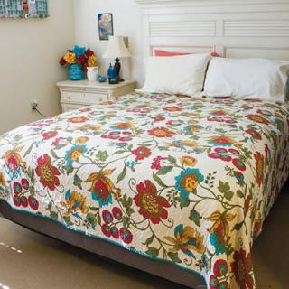 A cozy bedroom with a bed covered in a colorful floral quilt.