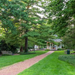 A peaceful park with a pathway leading to a gazebo surrounded by lush greenery.
