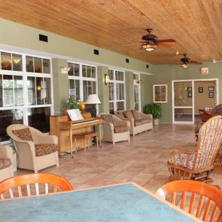 A cozy sunroom with wicker chairs, large windows, and ceiling fans providing a comfortable seating area.