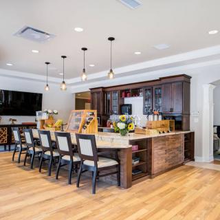 A modern kitchen with a large island and dining area, featuring elegant pendant lighting and sleek wooden cabinetry.