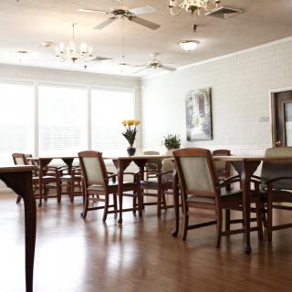 A spacious dining room with wooden furniture and elegant chandeliers.