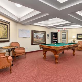 A luxurious billiard room with a pool table, comfortable seating, and elegant decor.