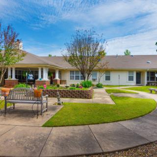 A well-maintained courtyard with a bench, pathways, and landscaping in front of a building.