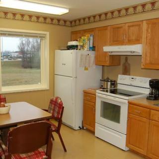 A cozy kitchen with wooden cabinets, a dining table, and a view through the window.