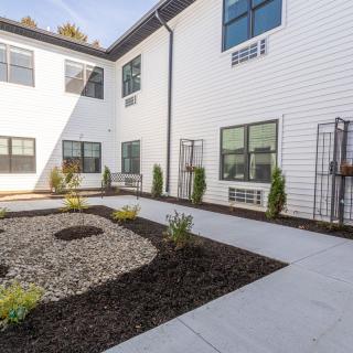 A modern building with a landscaped courtyard featuring gravel and young plants.